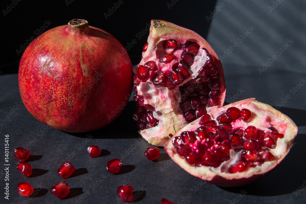 Pomegranate slices and garnet fruit seeds on a dark background Pomegranate slices and garnet fruit seeds on a dark background