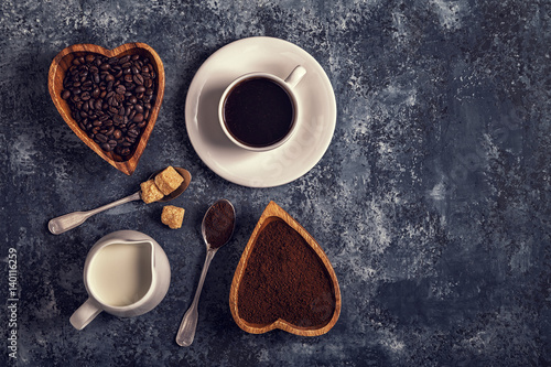 Coffee cup, beans and ground powder on stone background.