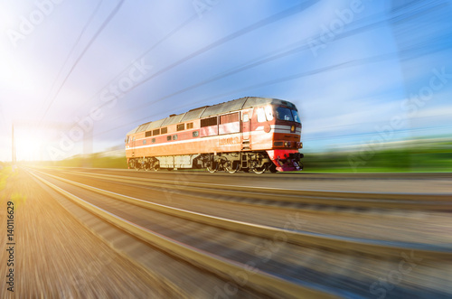 Lonely locomotive rushes by train at sunset