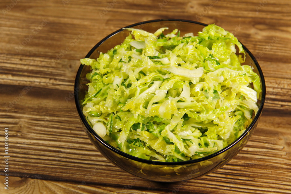Savoy cabbage salad in glass bowl on wooden table Savoy cabbage salad in glass bowl on wooden table