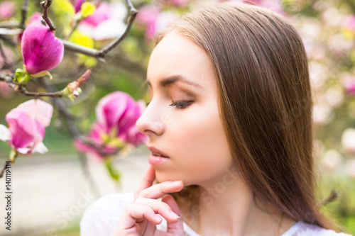 Young pretty girl relax in beautiful garden. Fantastic pink magnolias