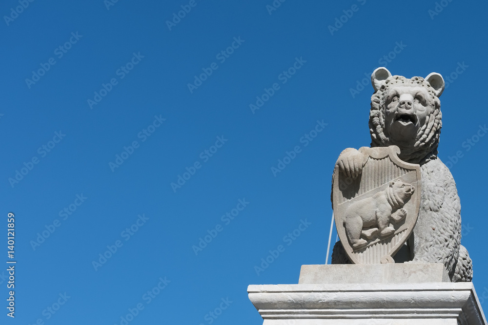Berner Bär aus Sandstein mit Wappen vor tiefblauem Himmel