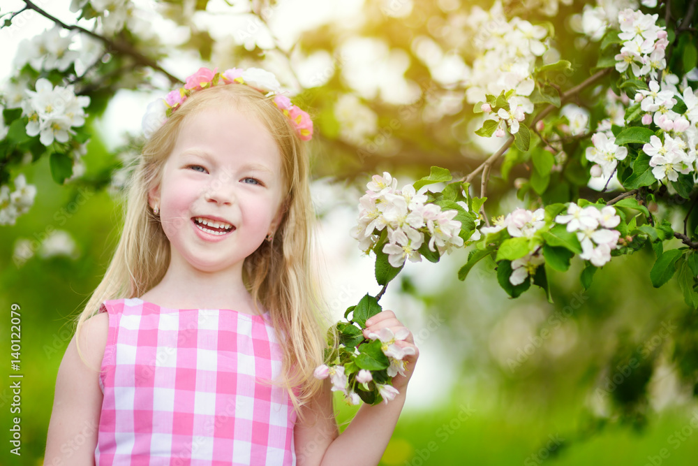 Adorable little girl in blooming apple tree garden on beautiful spring day Adorable little girl in blooming apple tree garden on beautiful spring day