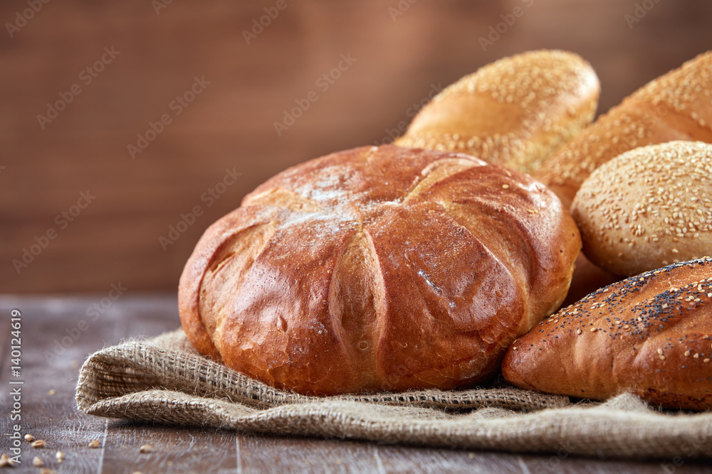 Fresh bread on a cloth linen with brown background on the wooden table with flour