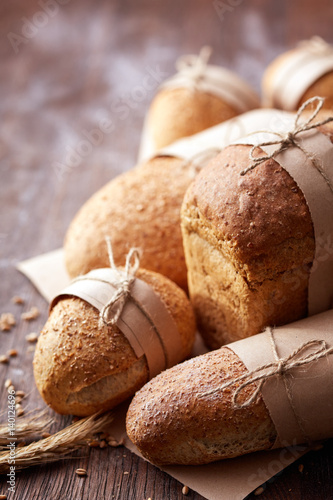 Many different bread in the baking paper and decorative rope on the wooden table, selective focus.