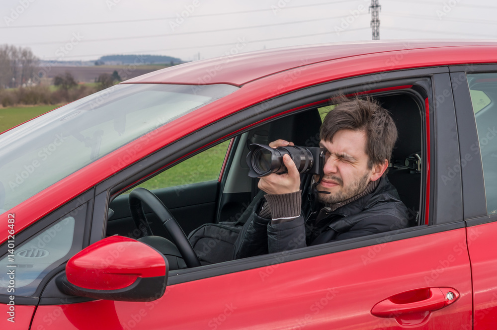 Detective is taking photo with camera from car. Detective is taking photo with camera from car.