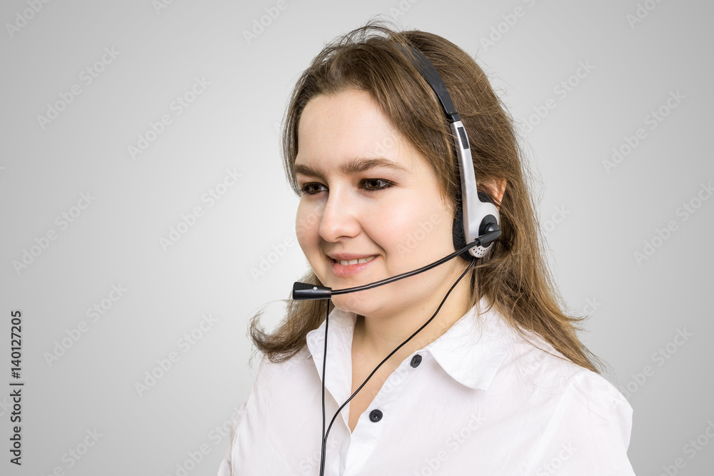 Telemarketing and customer service concept. Young smiling woman - operator on gray background. Telemarketing and customer service concept. Young smiling woman - operator on gray background.