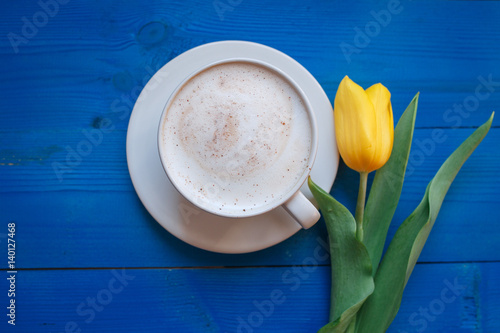 Coffee mug with yellow tulip flowers and notes good morning on blue rustic table from above, breakfast on Mothers day or Womens day .Spring  flowers bouquet photo