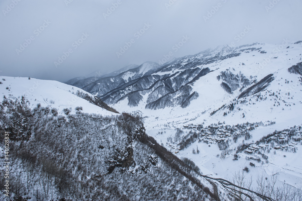 Snowy winter mountains in sun day. Caucasus Mountains, Georgia, from ski resort Gudauri