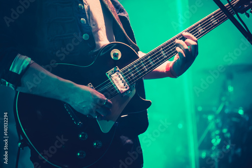 Electric guitar player on stage in green light