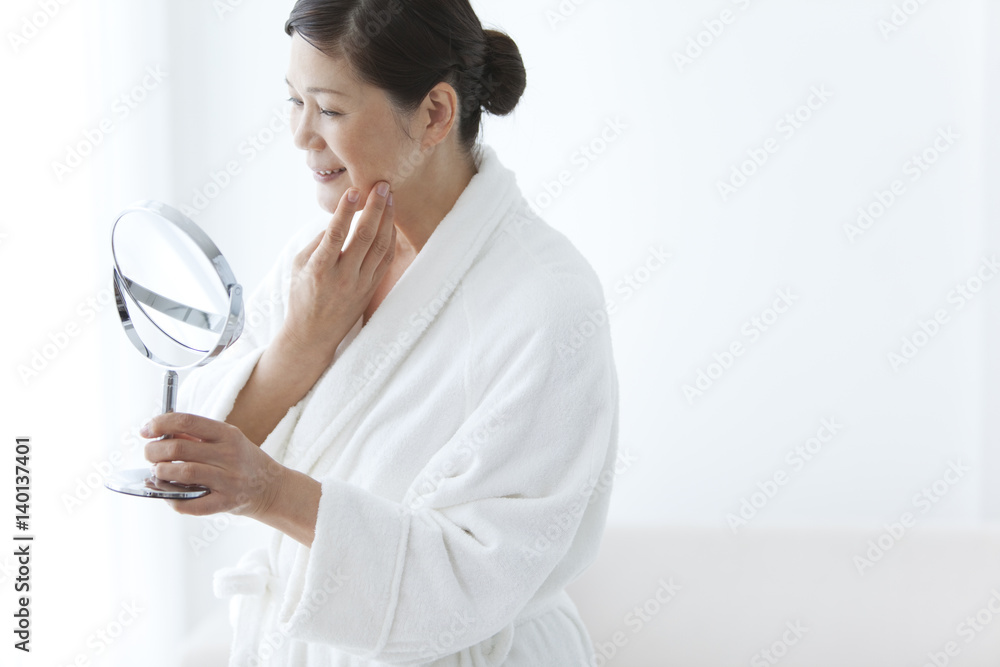 Middle-Aged Woman Wearing Bathrobe Looking Into Mirror Middle-Aged Woman Wearing Bathrobe Looking Into Mirror
