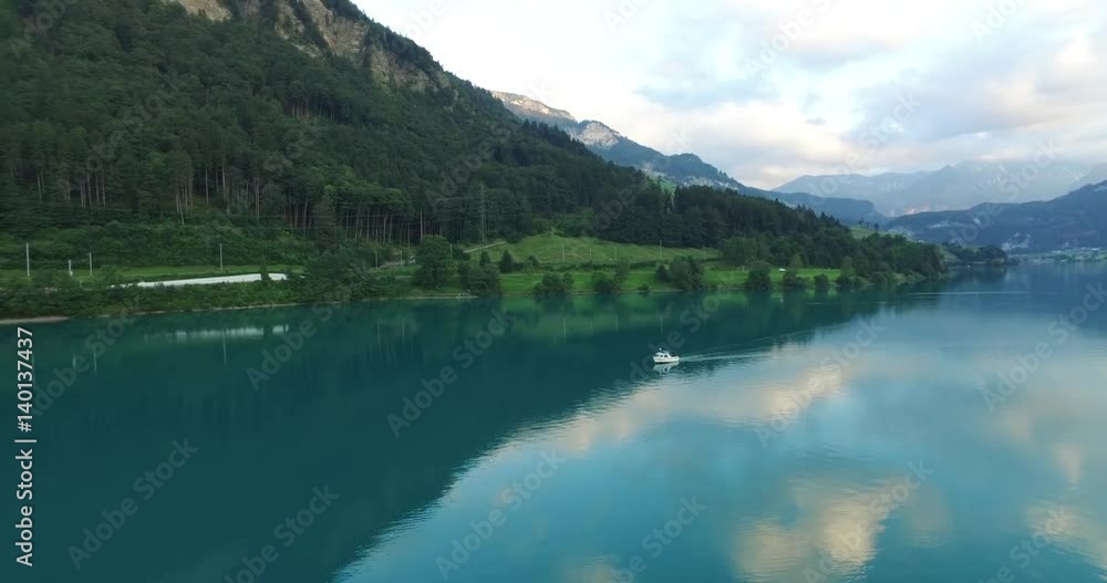Aerial view of boat floating on the river between the Swiss Alps mountains. Aerial view of boat floating on the river between the Swiss Alps mountains.