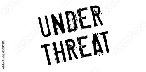 Under Threat rubber stamp. Grunge design with dust scratches. Effects can be easily removed for a clean, crisp look. Color is easily changed.