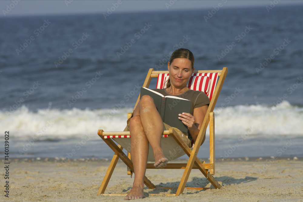 Woman sitting on a beach chair while reading
