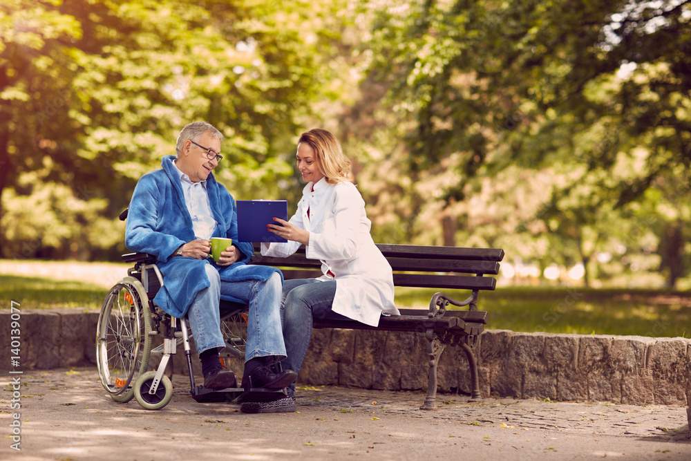 nurse talking with patient in wheelchair checking up the history of the disease. nurse talking with patient in wheelchair checking up the history of the disease.