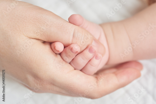 A newborn baby holding his mother's hand
