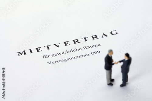Businessmen figurines standing on a rental agreement shaking hands