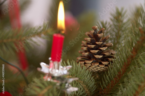 Burning candle and pine cones on Christmas tree