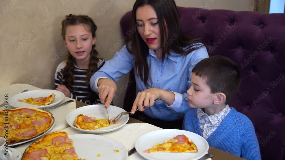 Mother and her two children eating pizza in cafe Mother and her two children eating pizza in cafe