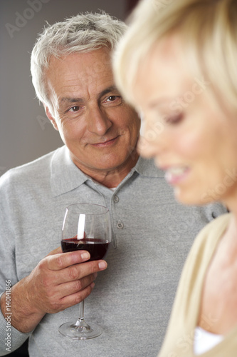 Gray-haired man and blonde woman drinking red wine, close-up © Gudrun