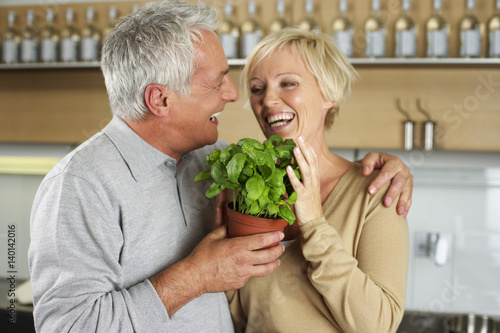 Man and woman holding a pot of basil together, close-up