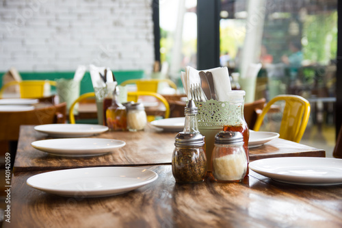 setup wooden table, plates, utensils, and condiments
