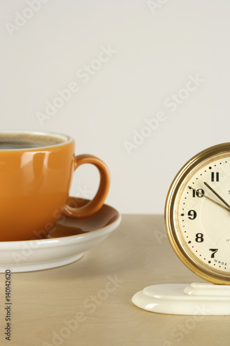 Part of an alarm clock and a cup of coffee