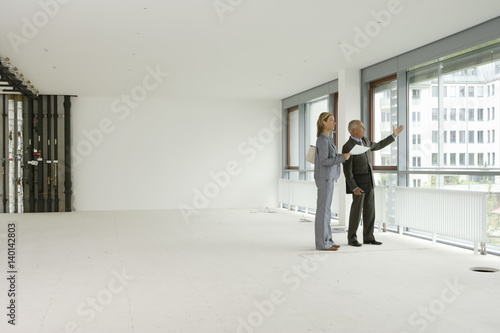 Elderly manager and blond business woman looking out of window in an empty office