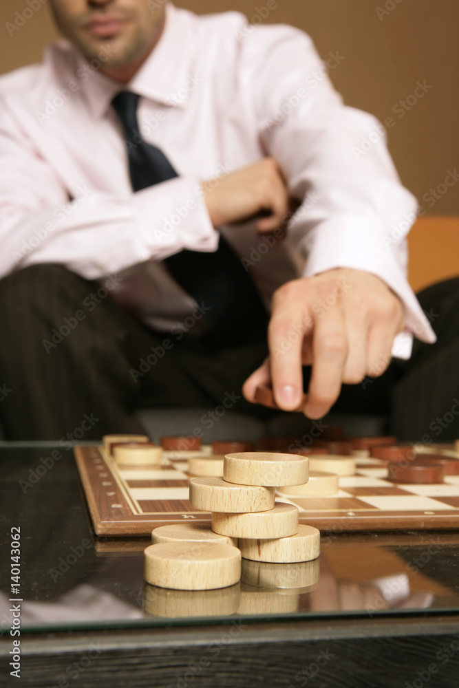 Businessman playing checkers, token in foreground