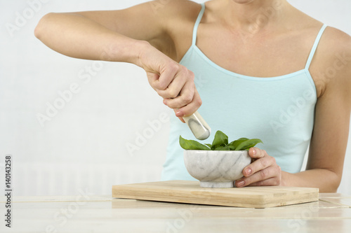 Woman crushing basil in a mortar with a pestle  © Gudrun