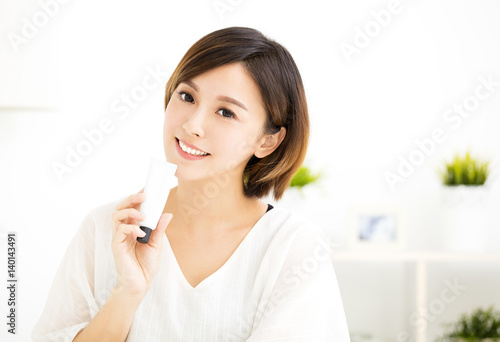 smiling young woman showing skincare products