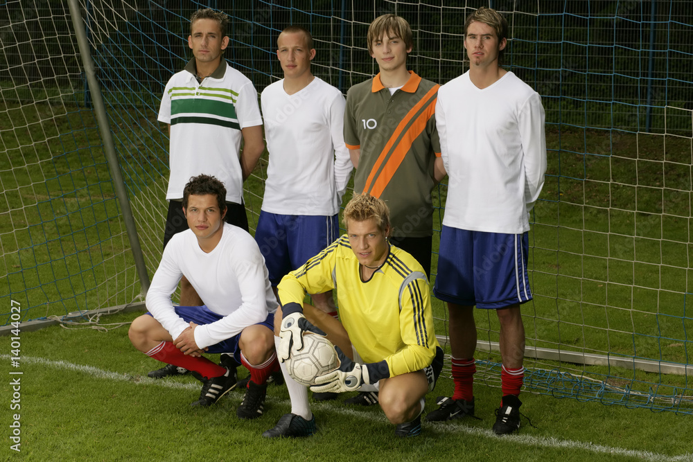 Five footballers and a goalkeeper standing on a pitch