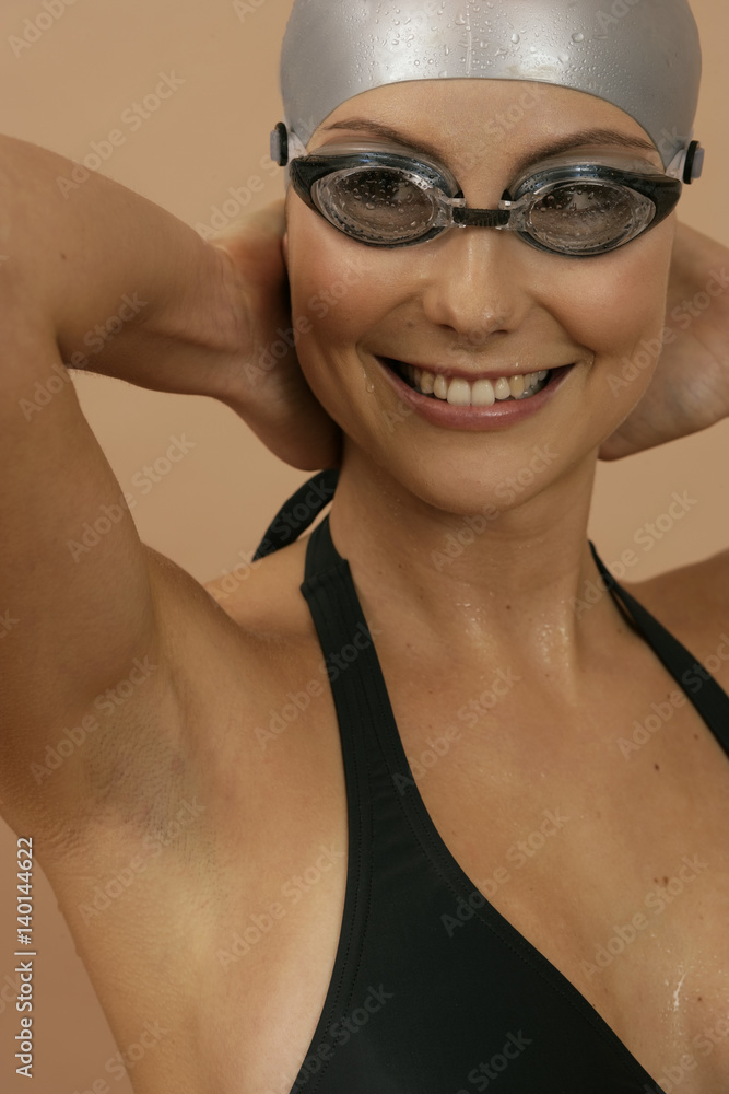 Smiling female swimmer wearing a bathing cap and goggles