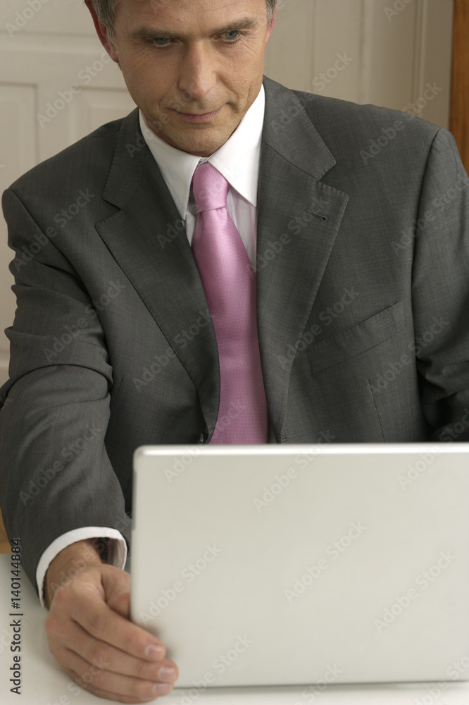 Mature adult businessman is sitting at a laptop, close-up Mature adult businessman is sitting at a laptop, close-up