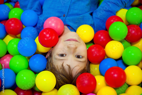 Happy little kid boy playing at colorful plastic balls playground high view. Funny child having fun indoors. photo