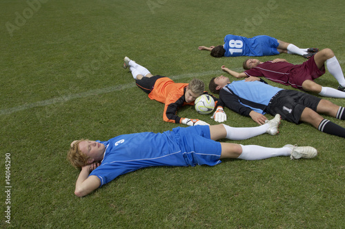 Exhausted kickers lying on soccer field