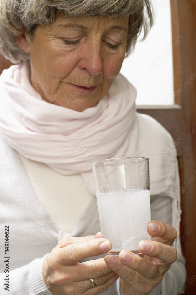 Sick woman holding a glass of water with an effervescent tablet Sick woman holding a glass of water with an effervescent tablet