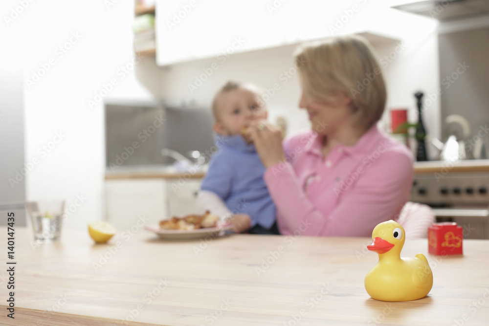 Mother feeding son, rubber duck in foreground