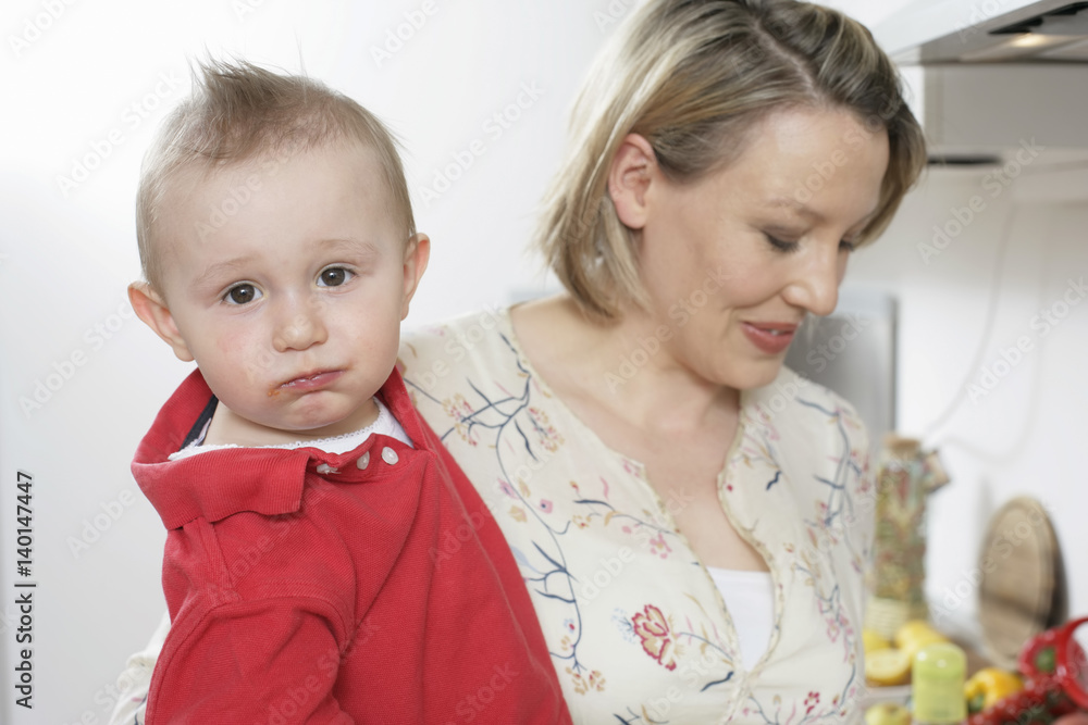 Mother carrying son on arm, he looking at camera Mother carrying son on arm, he looking at camera
