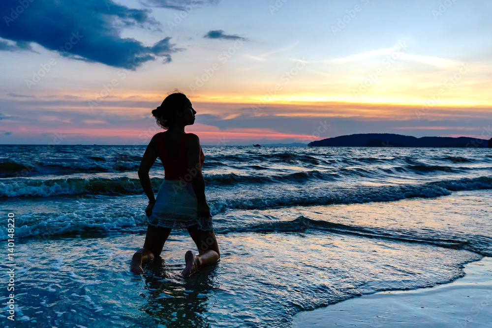 Young happy woman in the sea at sunset 
