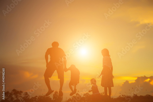 a silhouette of a happy young girl child the arms of his loving mother for a hug, in front of the sunset in the sky on a summer day. 
