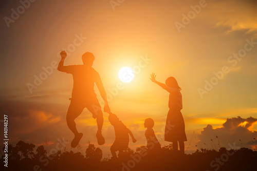 a silhouette of a happy young girl child the arms of his loving mother for a hug  in front of the sunset in the sky on a summer day. 