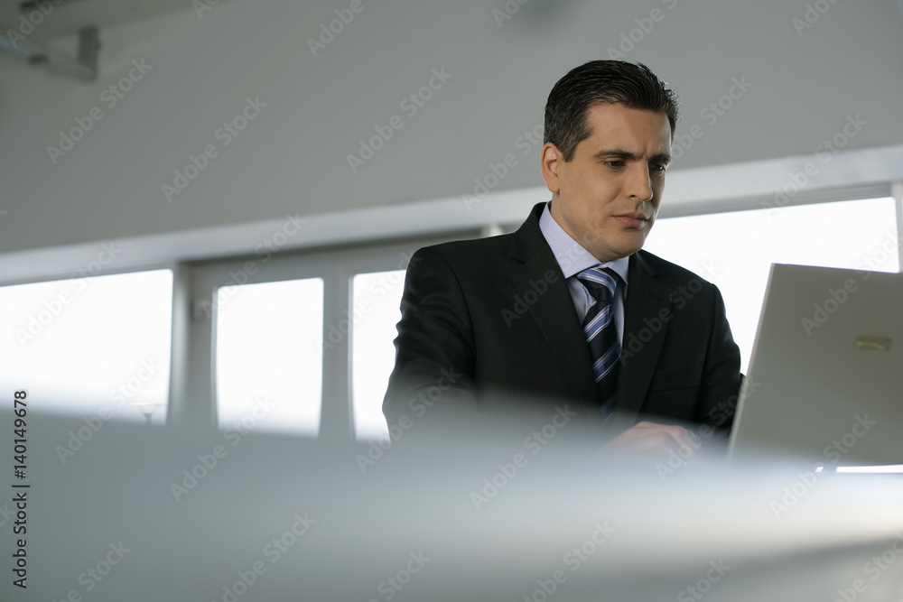 Businessman standing on a counter working on a laptop Businessman standing on a counter working on a laptop