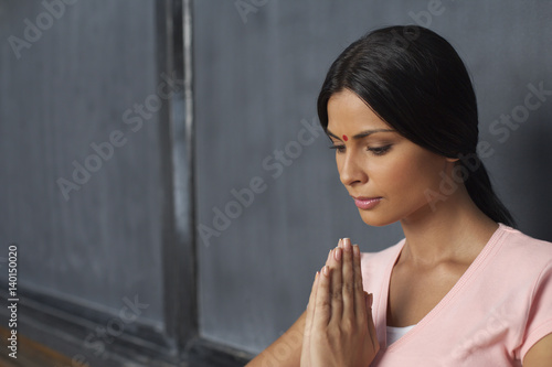 Indian woman with her hands folded in front of a blackboard photo