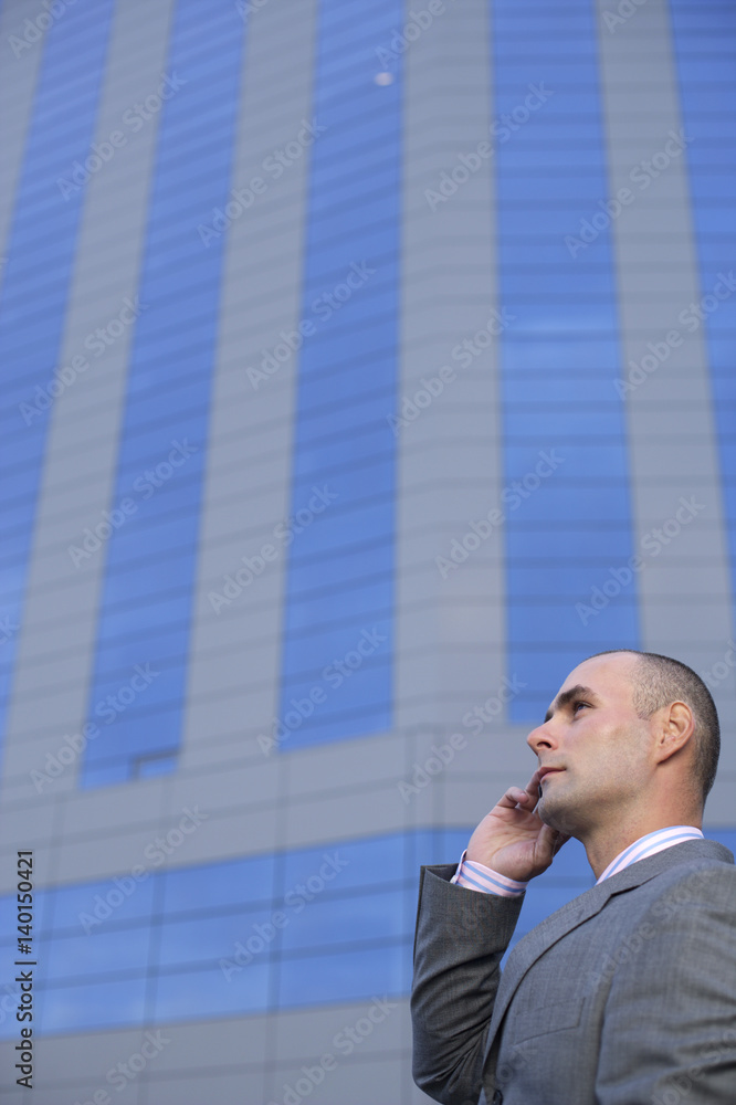 Businessman phoning with a mobile phone in front of an office building Businessman phoning with a mobile phone in front of an office building