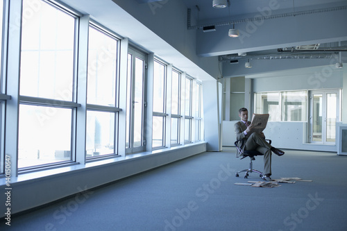 Businessman reading a newspaper in an empty office