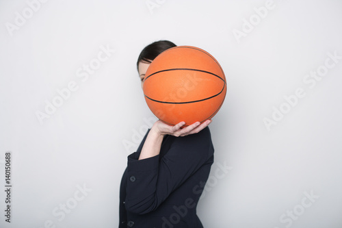 Businesswoman covering face with a basketball © Gudrun