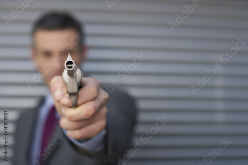 Businessman aiming with a gun at camera