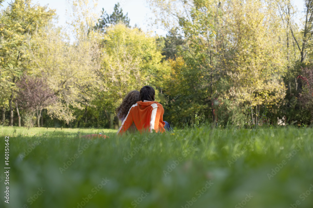 Teenage boy and girl sitting together on a meadow, selective focus Teenage boy and girl sitting together on a meadow, selective focus