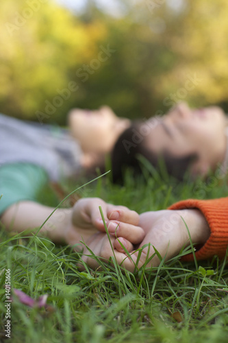 Teenage boy and girl lying on a meadow head to head, selective focus